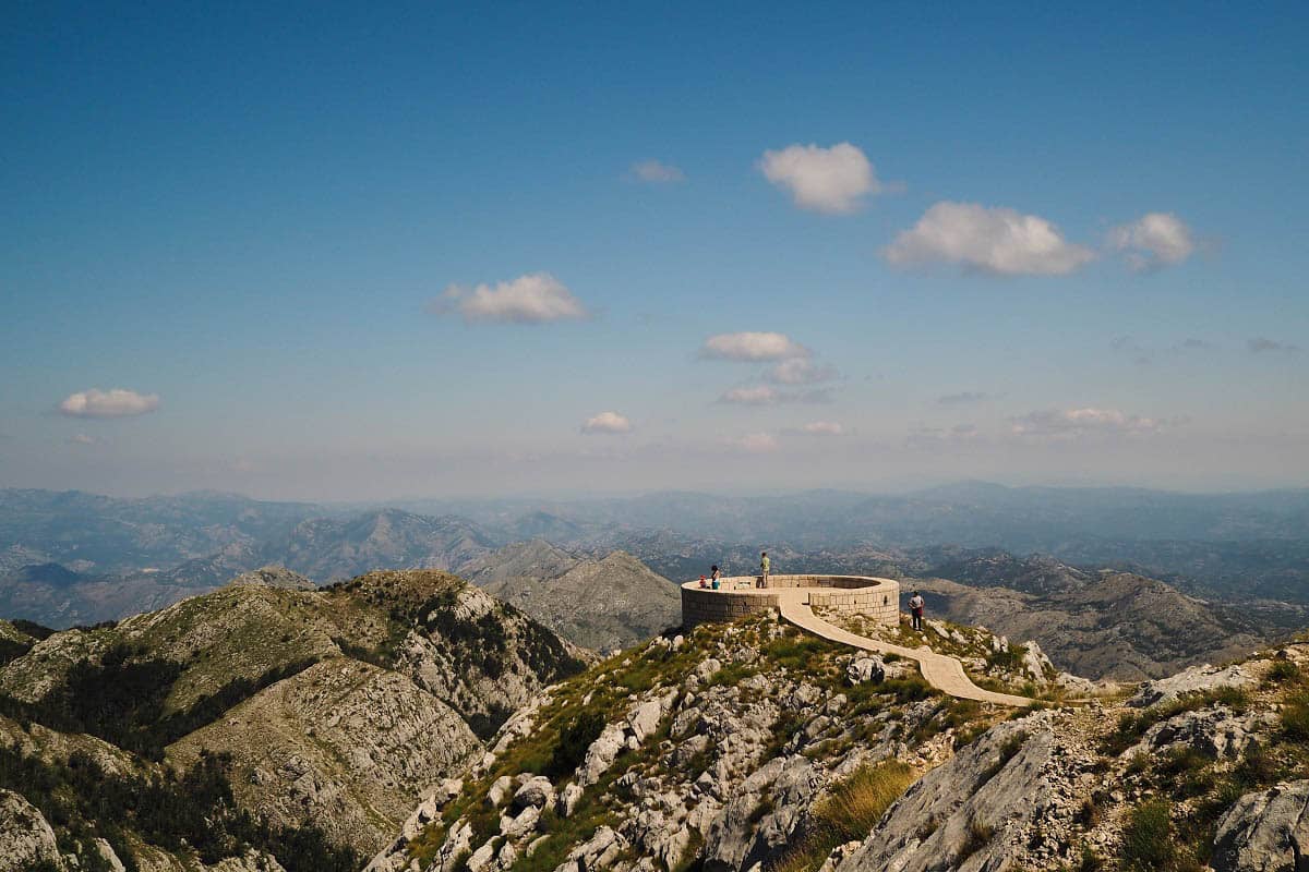 A beautiful panorama of hills and mountains surrounding Lovćen Mausoleum, dedicated to poet and ruler of Montenegro. Tourists are enjoying the time at leisure.
